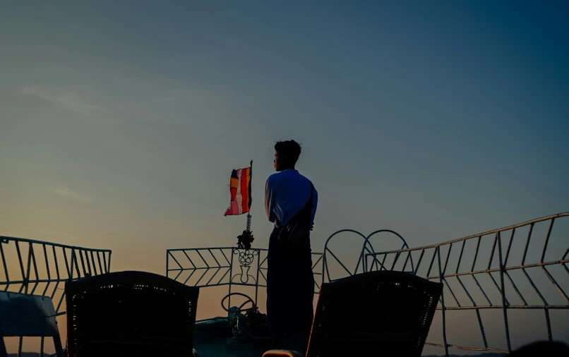 the man stands near two chairs holding a flag