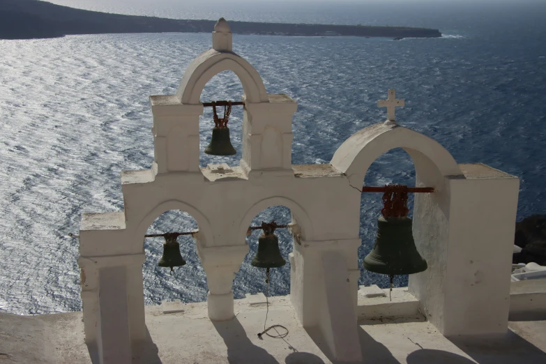 two bells on top of a bell tower near the ocean