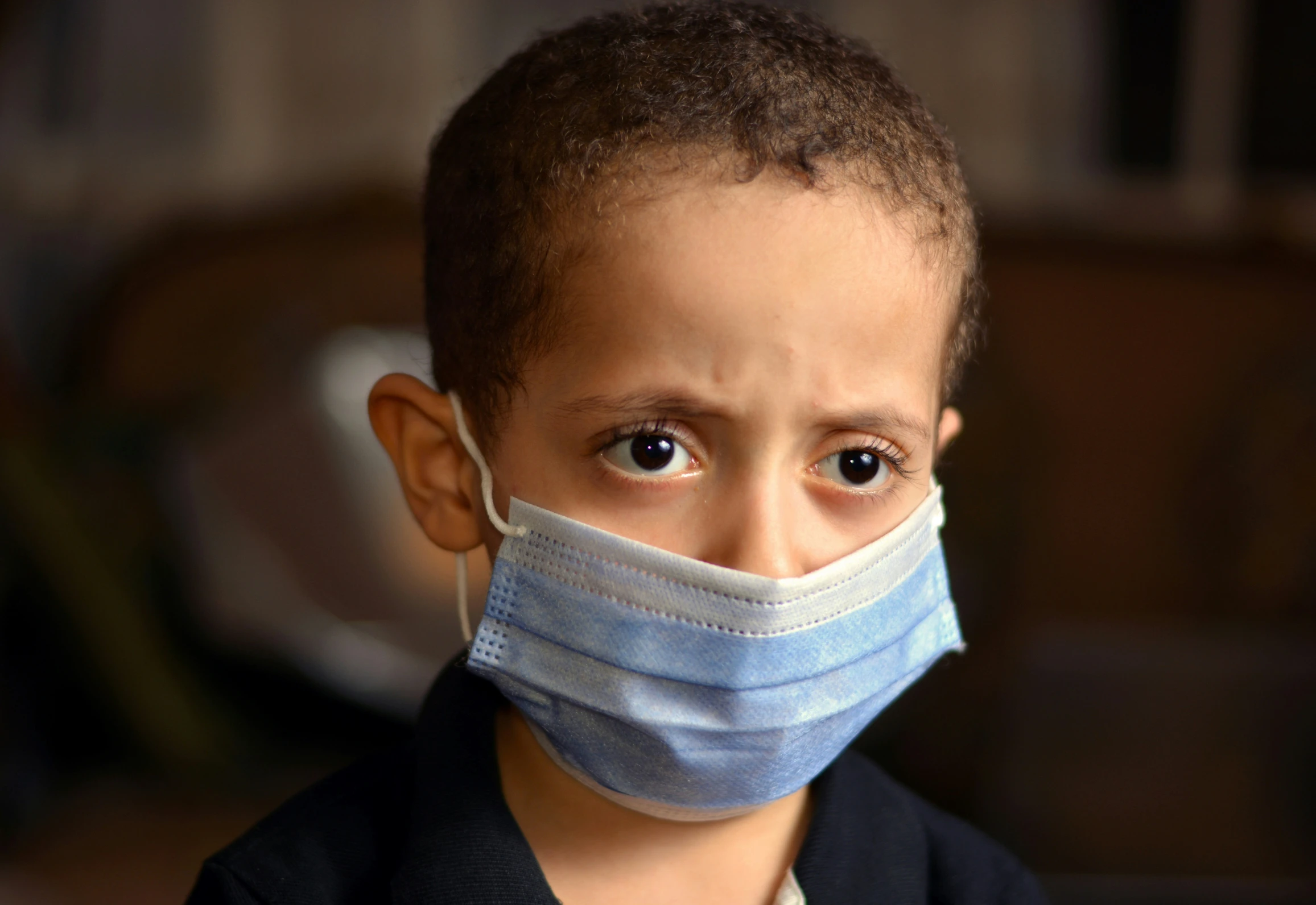 an adorable little boy wearing a face mask