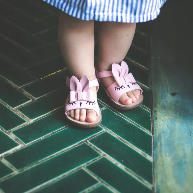 two legs wearing sandals and slippers on a tiled floor