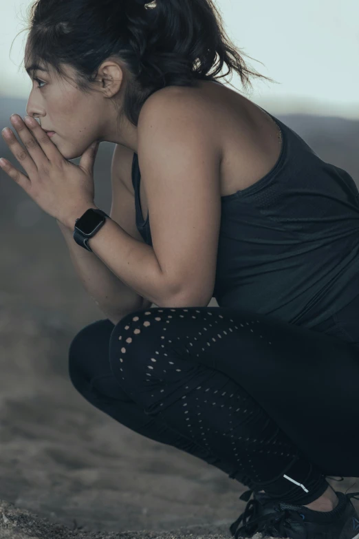 a woman sitting on top of a beach near her hands clasped together