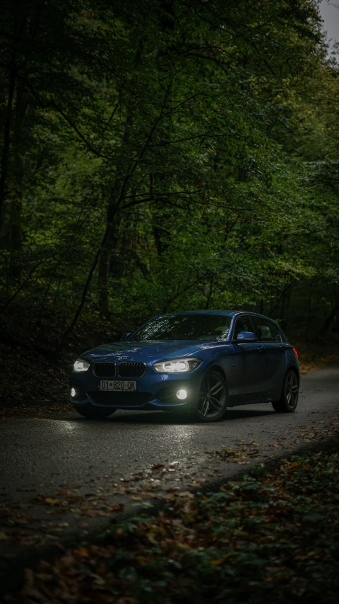 a blue car parked on the side of the road in the rain