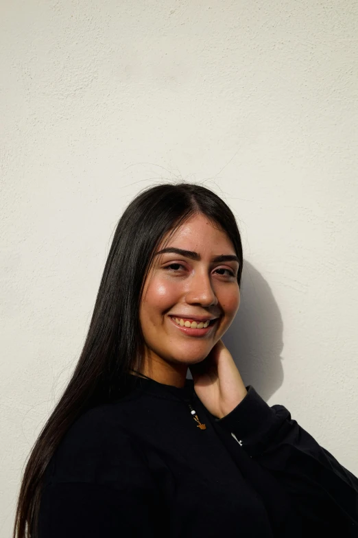 a woman smiling at the camera with her hand under her chin