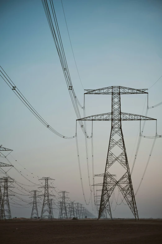 a person walking in the dirt and some high voltage power lines