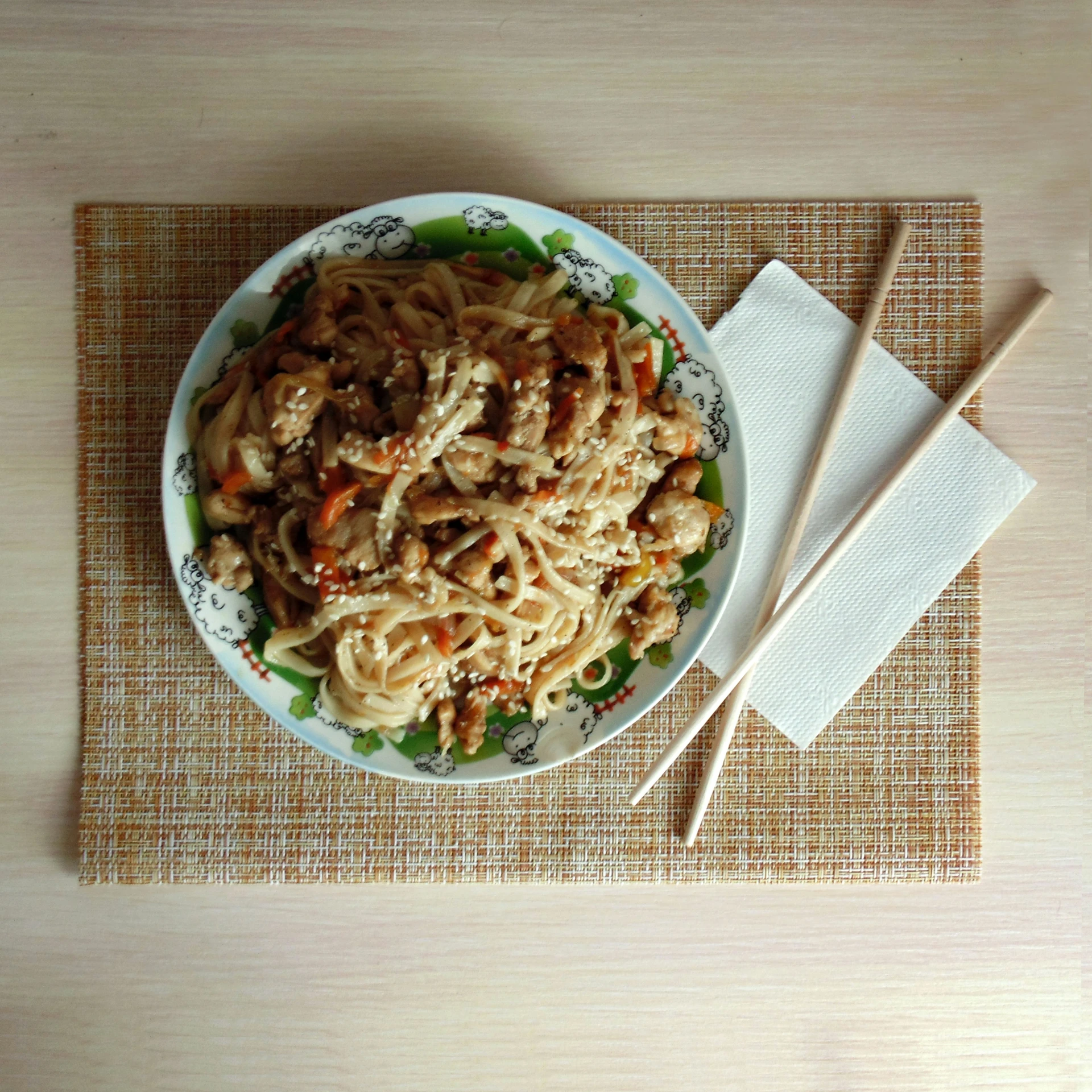 a plate of food sitting on a place mat with chopsticks