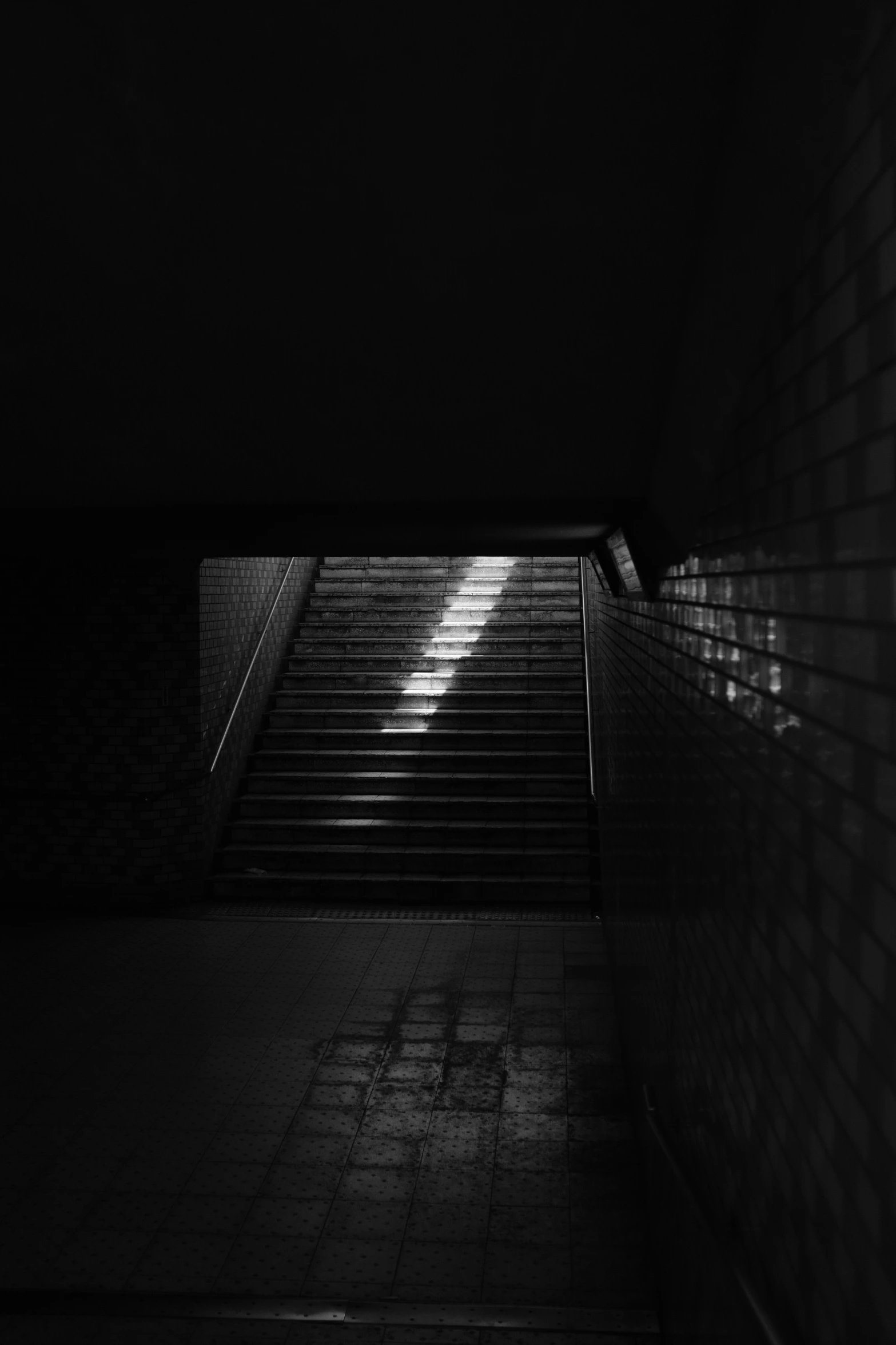 an escalator with a brick wall and a staircase