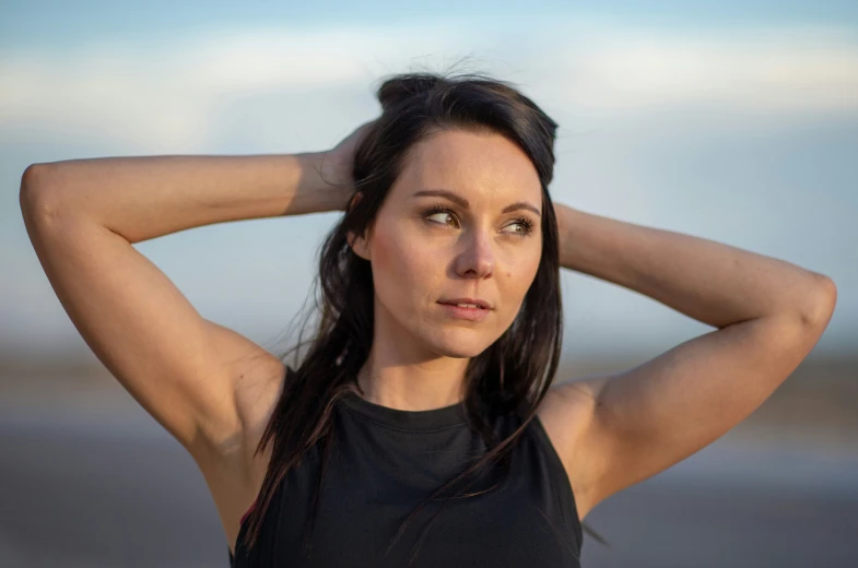 a woman poses in front of the ocean with her head against her hair