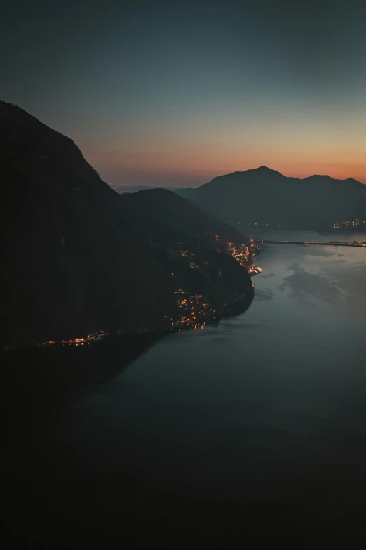 a dark, mountainous area that is in the foreground with an island in the background, at sunset