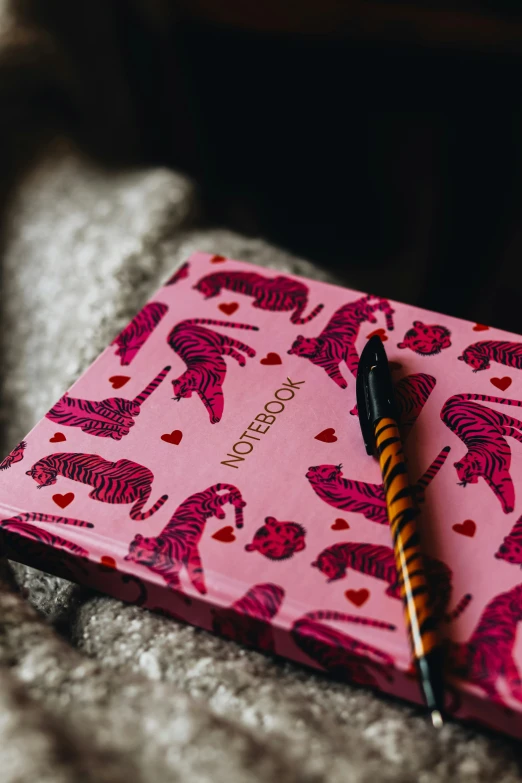 a pen laying on top of a pink notebook