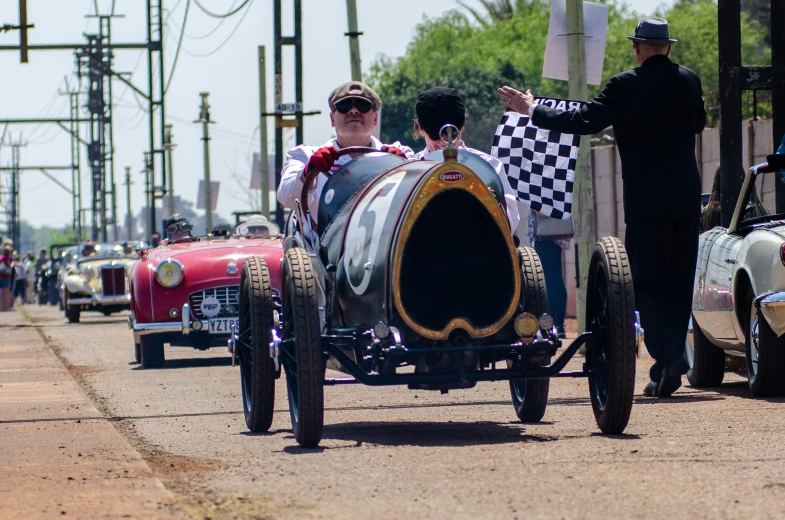 men driving an old race car with a checkered front