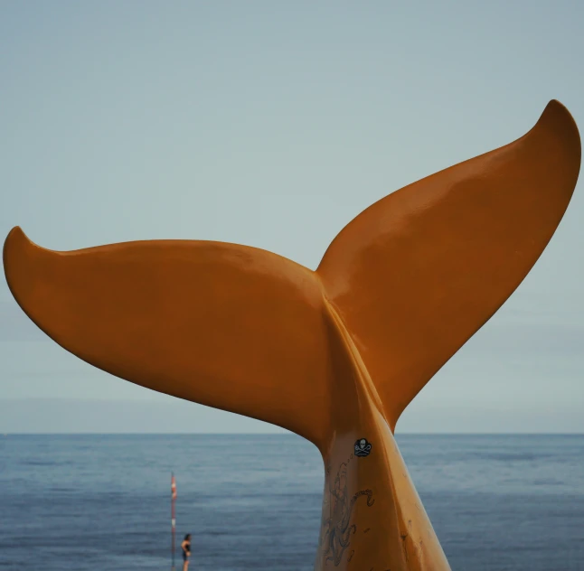 a huge yellow whale tail is by the ocean