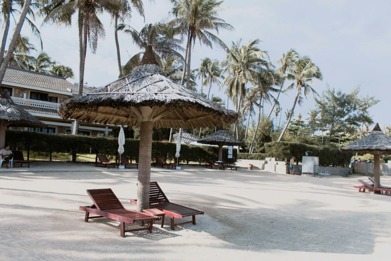 three chairs are sitting under a straw umbrella on the beach