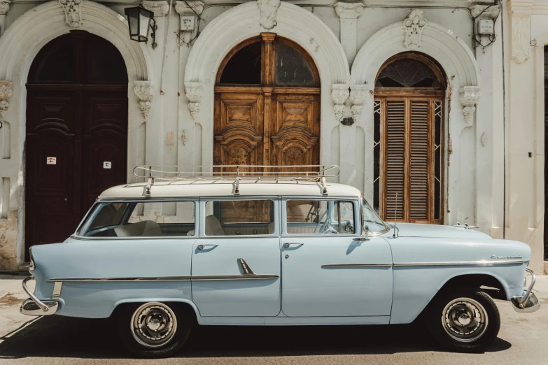 an old blue car is parked in front of the entrance to a house