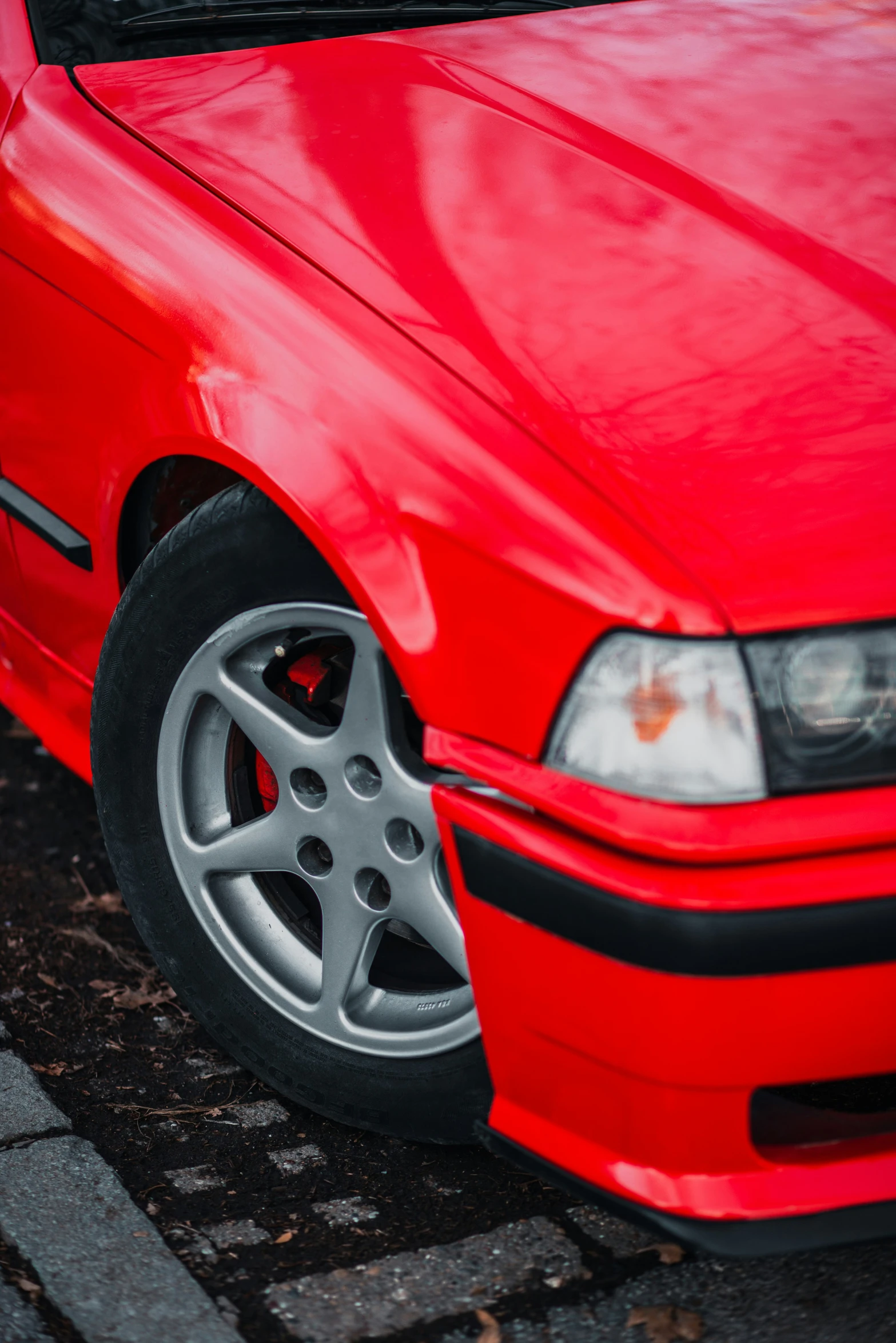 a close - up po of the front end of an older red car