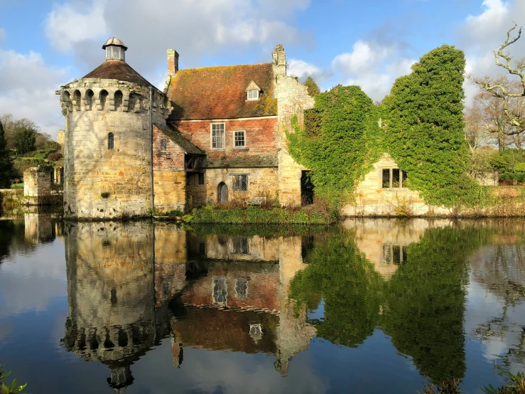 a castle sits beside a large pond with a reflection