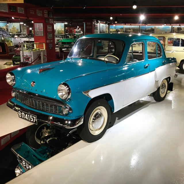 a small blue car with white paint sits on display