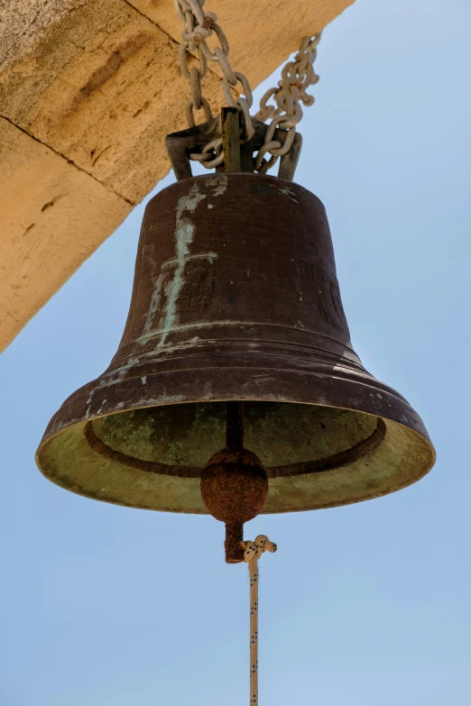 a metal bell is being held to a beam