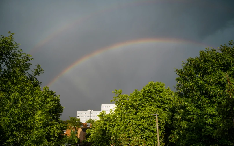 two rainbows over some trees and buildings