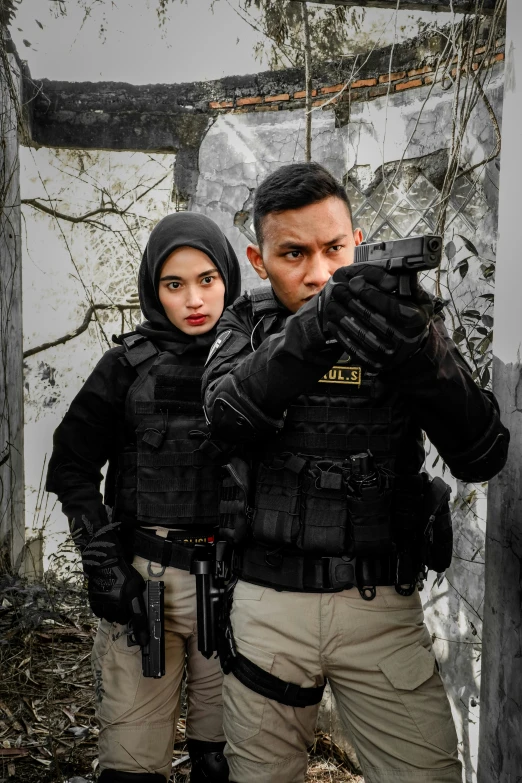 two people wearing swat suit, holding guns, look at the camera