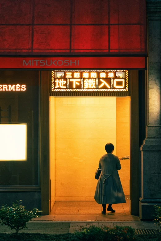 a woman in grey coat standing in front of building