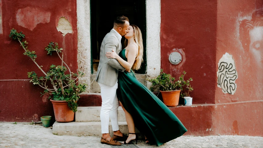 a couple kissing and emcing outside the window of a building