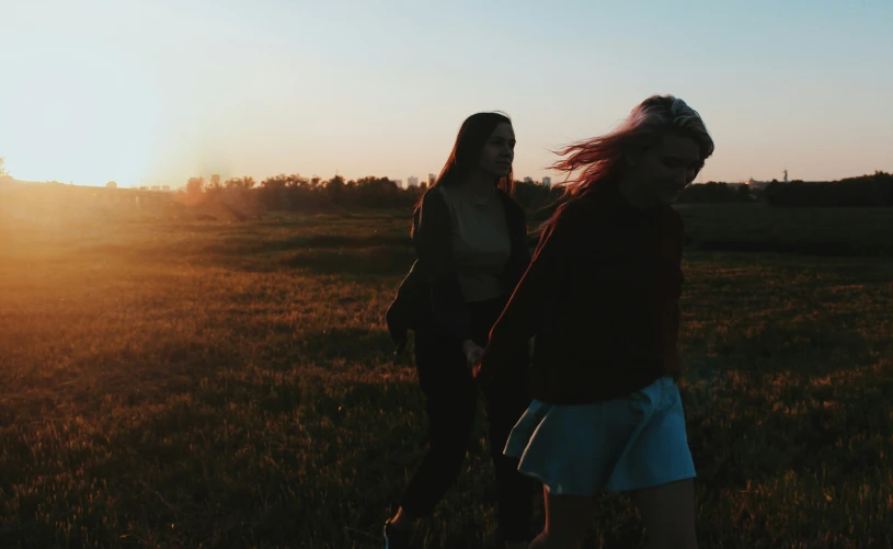 two women standing on top of a lush green field