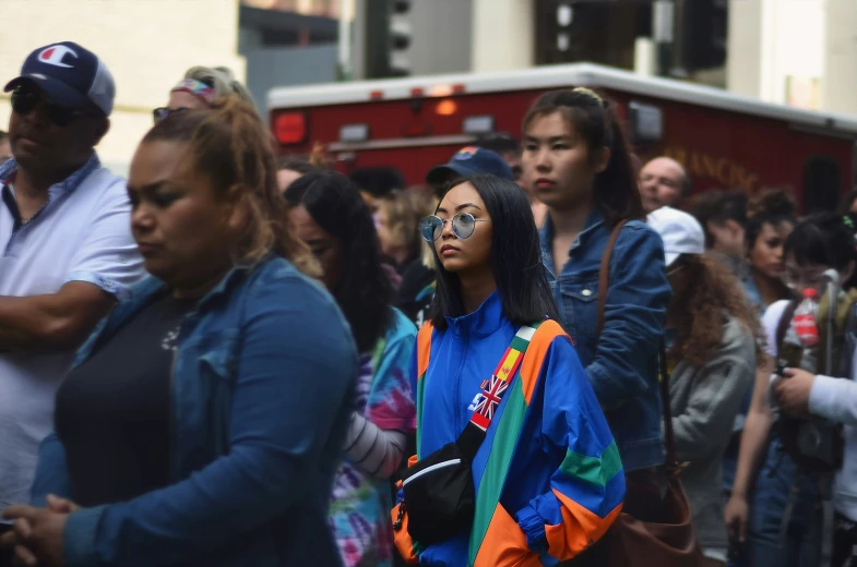 many people are walking down the street by the fire truck