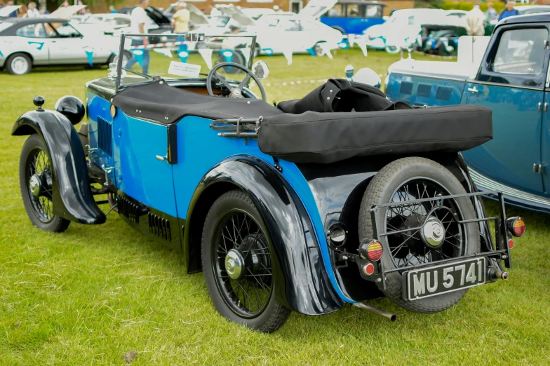 a vintage blue and black automobile parked in the grass