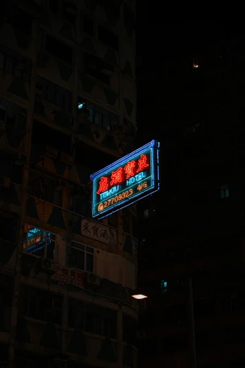 large illuminated sign on building in front of dark night