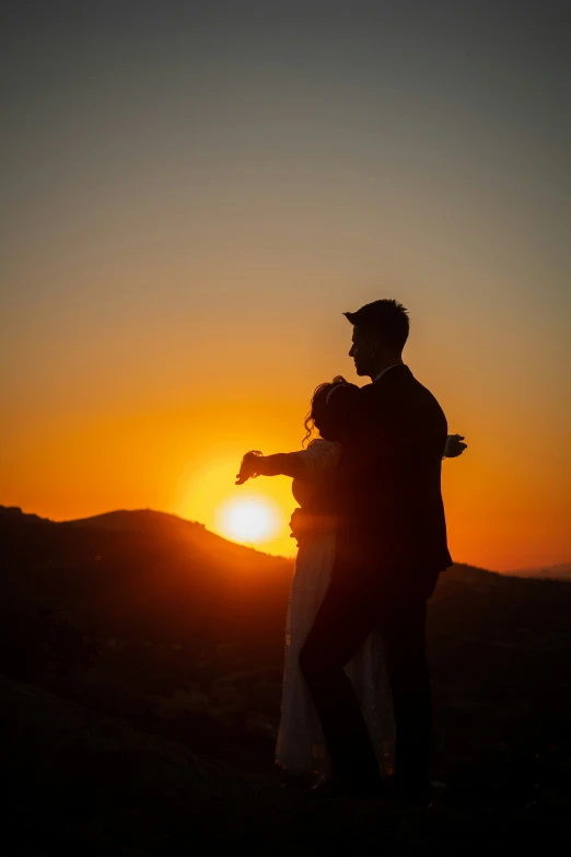 two people stand in the sunset, back lit by the setting sun