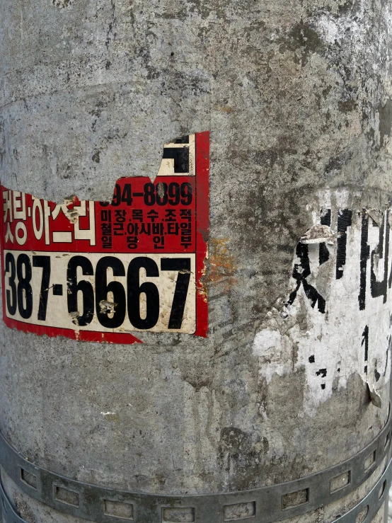 there is a red and black name tag on a concrete pillar