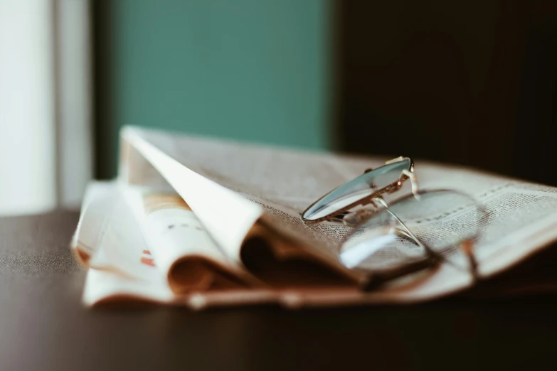 a pair of glasses are on top of an open newspaper