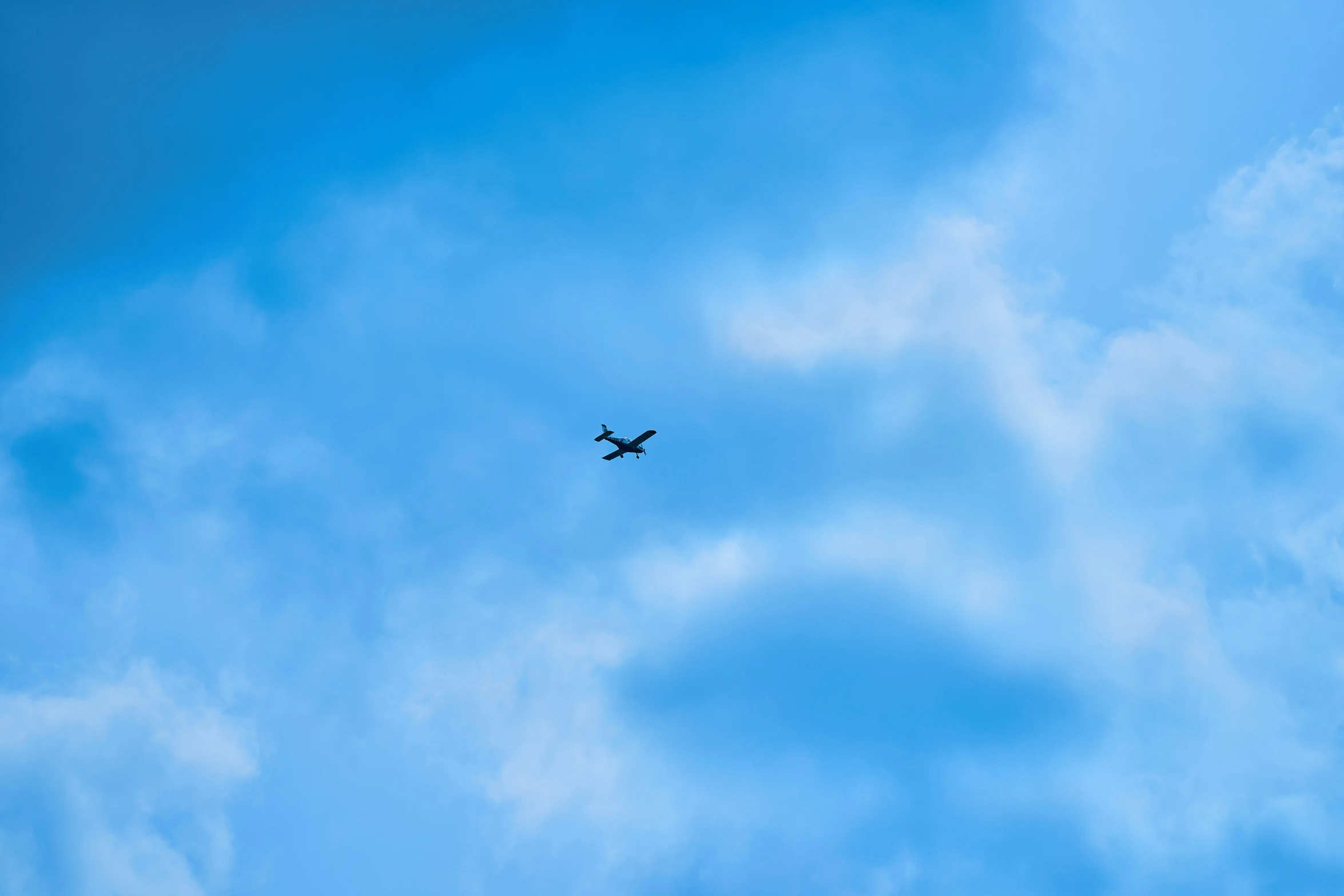 an airplane flying in the sky with white clouds