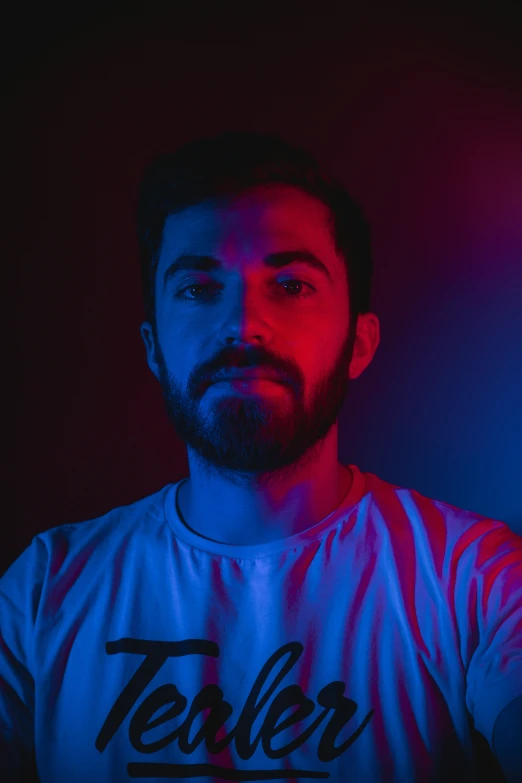 a bearded man poses for a po in a black room