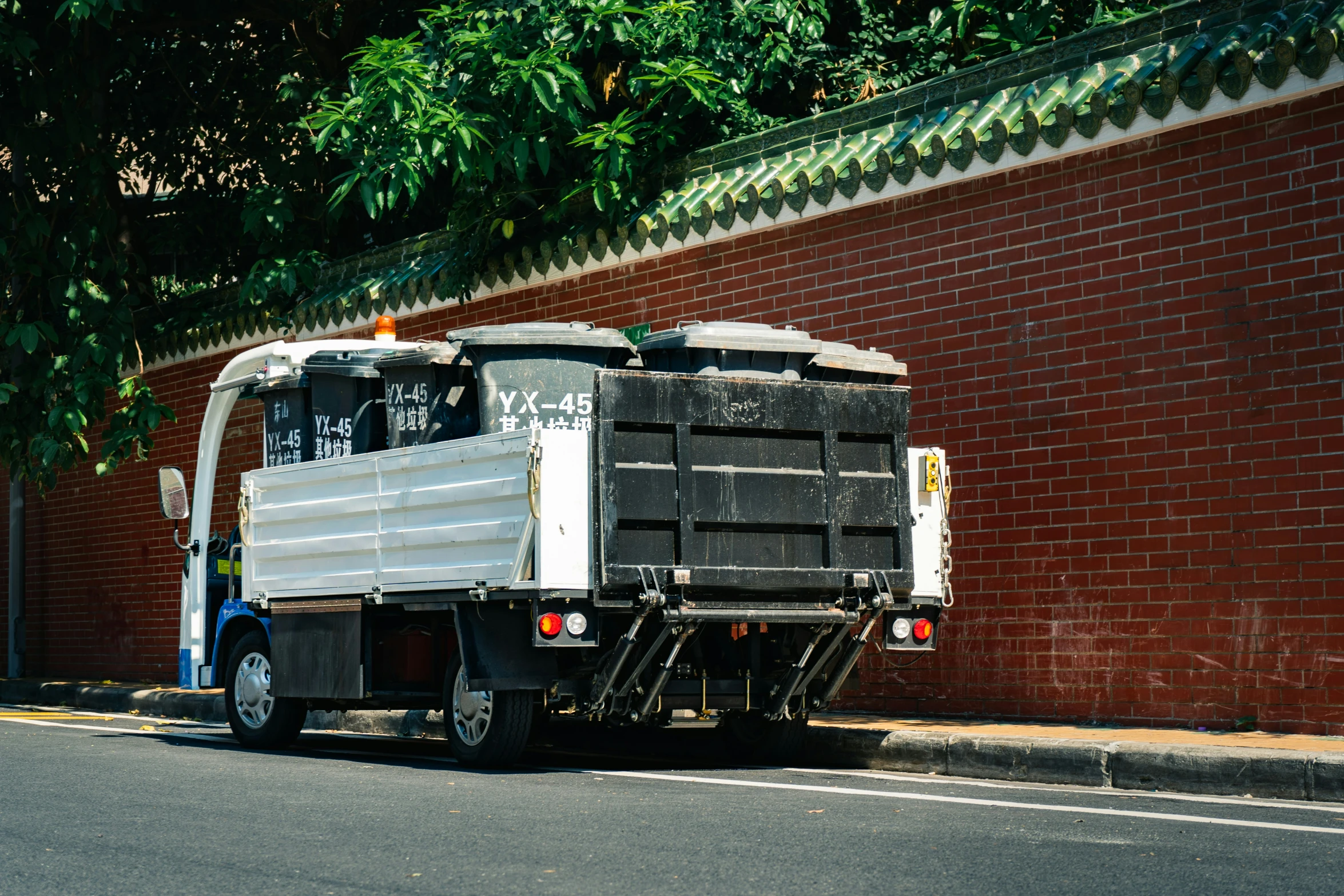 the white truck is driving down the road by a wall