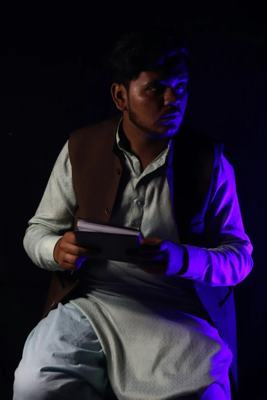 a man sitting down on the floor holding a folder