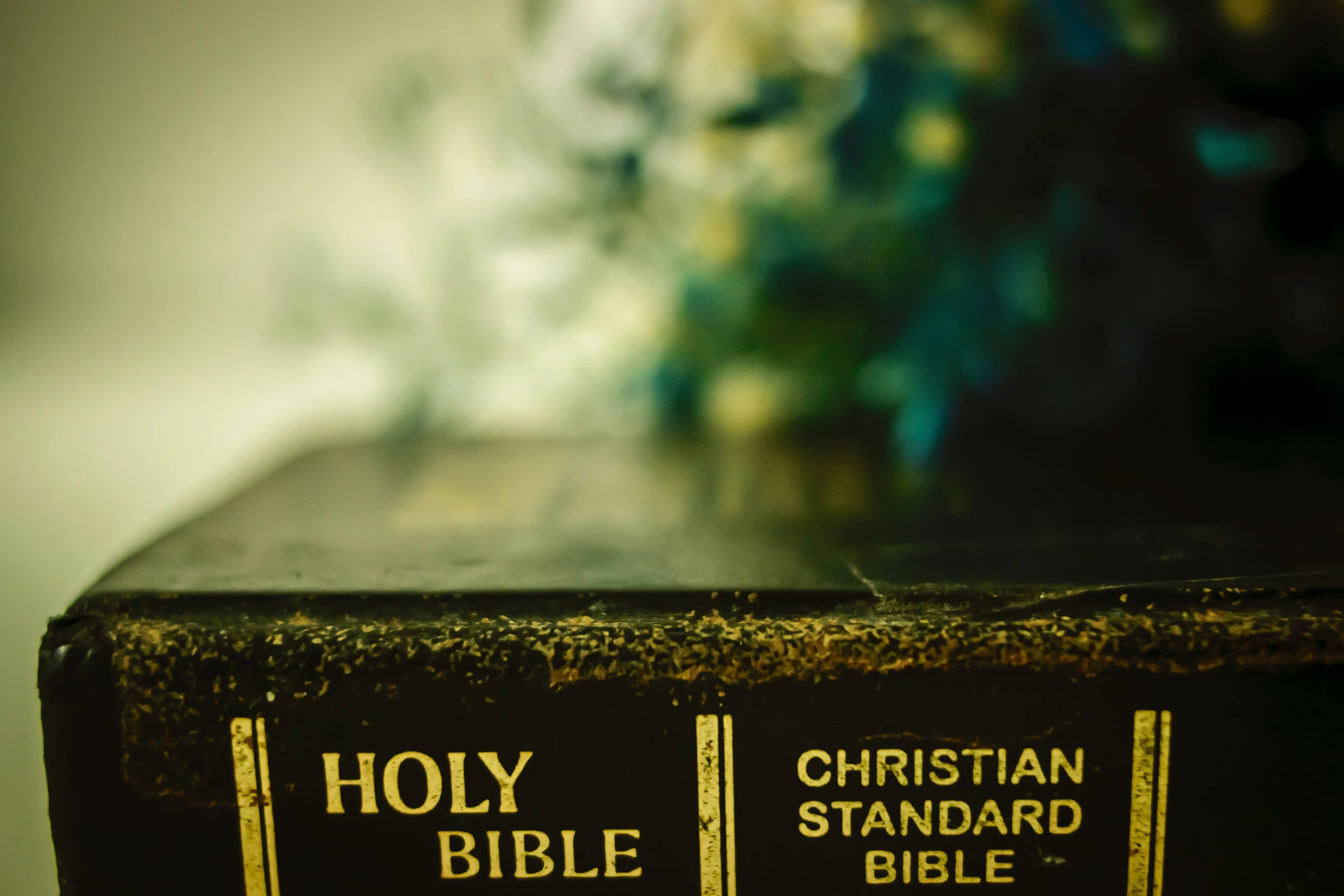 a bible with yellow lettering is on a table