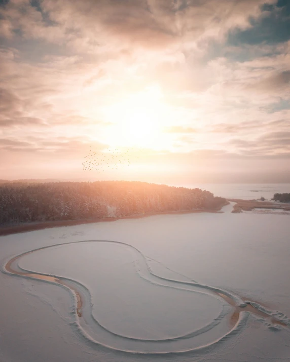 the sun is setting over the large snowy field