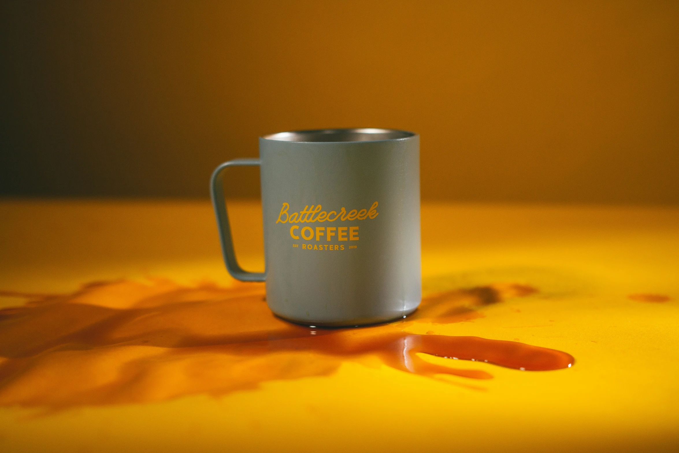 a metal cup on top of yellow painted leaves