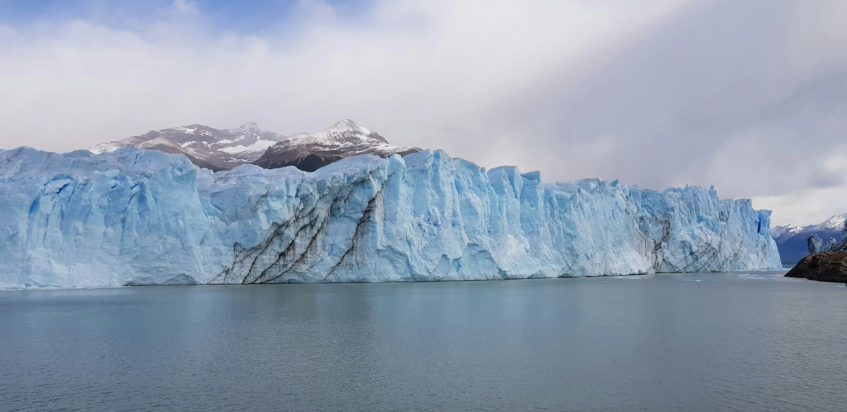 a large iceberg with mountains in the distance