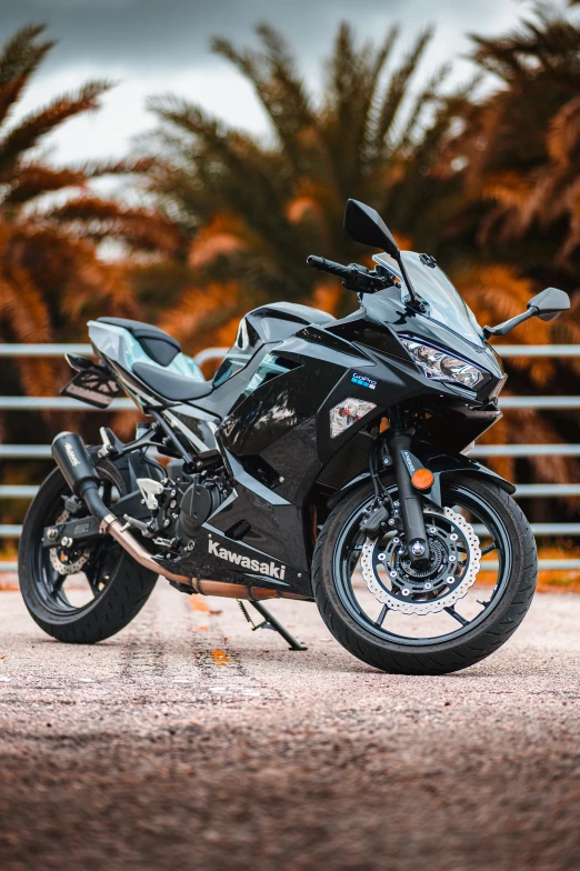 black motorcycle parked in front of an empty fence