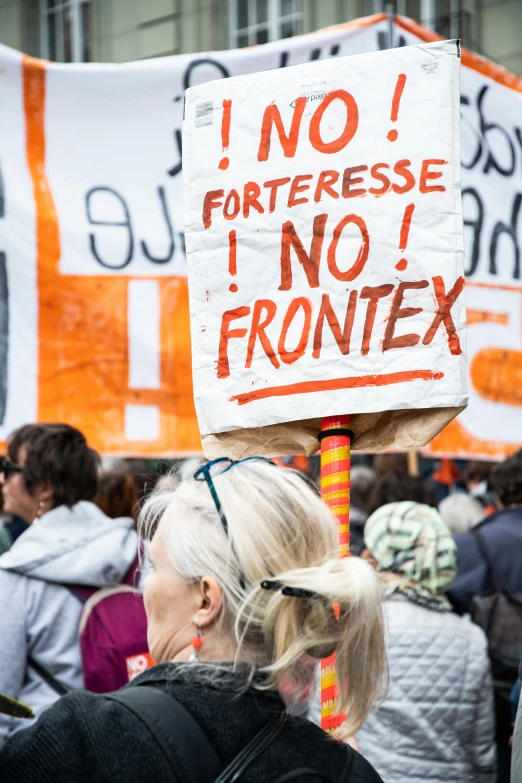 woman holding a sign with a political message written in orange