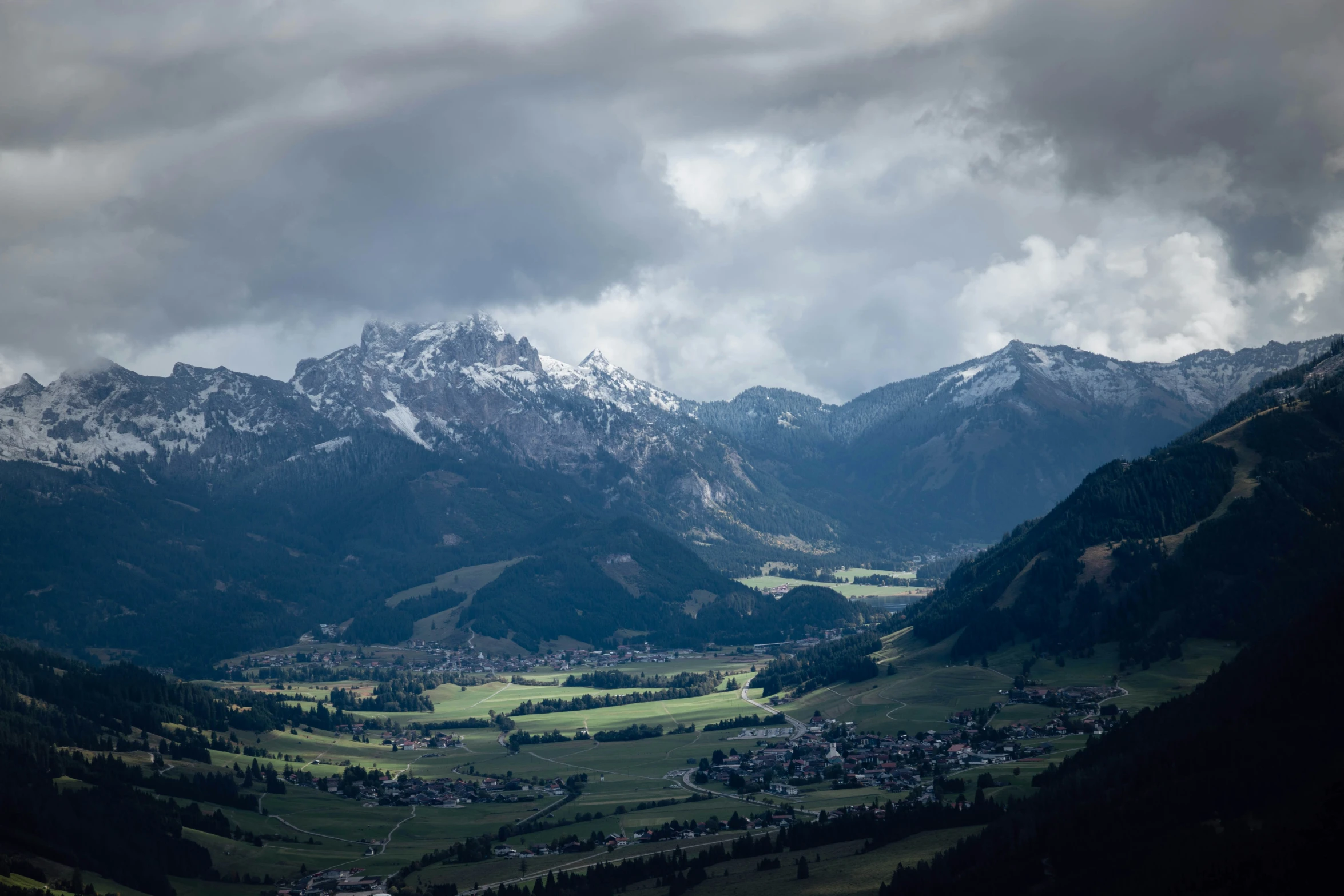 a scenic view of mountains with snow and a valley in the foreground