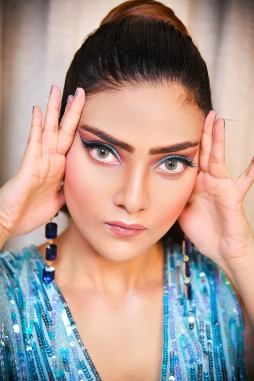 a young woman has her eyes partially closed, holding her hand at her temple