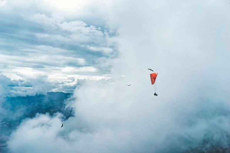 two para - gliders are flying in the cloudy sky