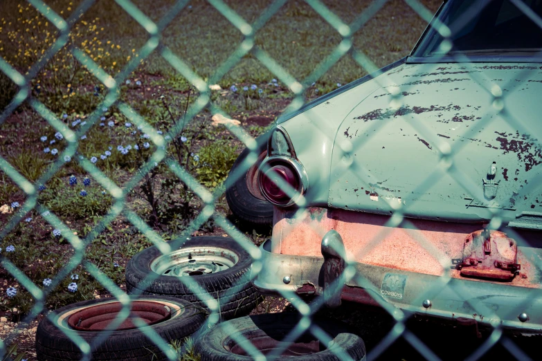 an old car is sitting behind some rusty tires