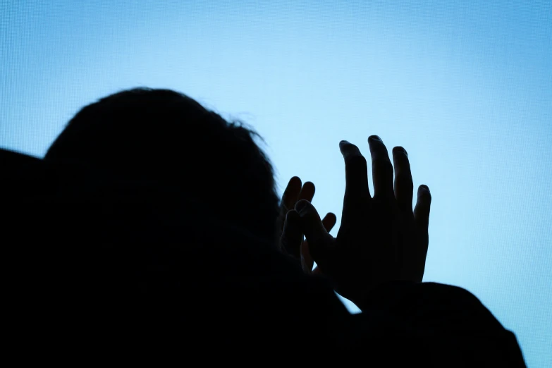 silhouette of person with hands raised in front of a flat screen