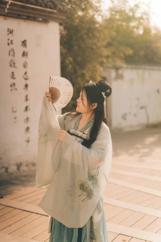 woman in oriental outfit posing holding a large fan