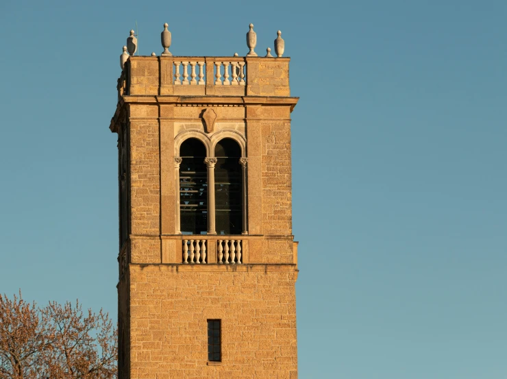 the tall tower with three birds sitting on it is next to a tree