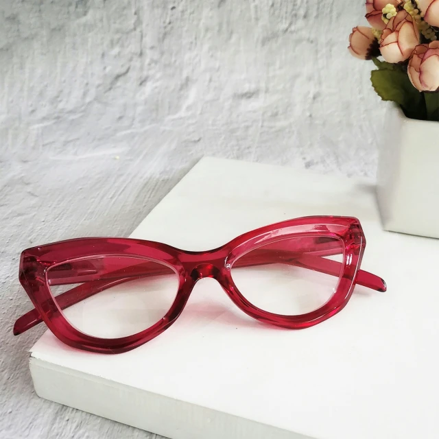 a pair of red glasses with clear, cat - eye frame frames on a white surface